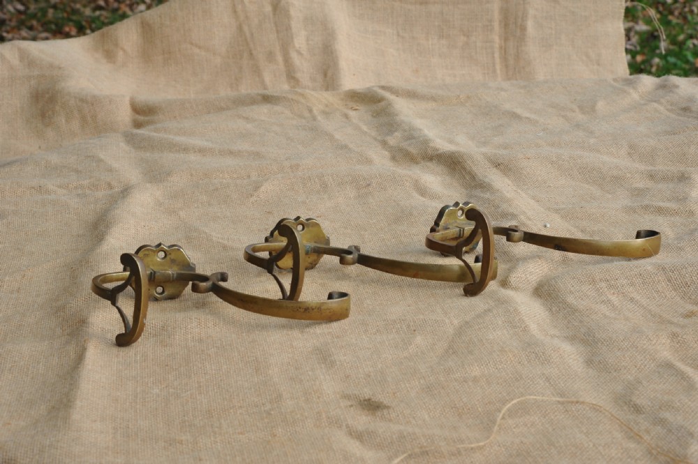 A set of three antique French cast bronze wall-mounted hat and coat hooks with scrolled upper arms and shaped lower pegs. View IV
