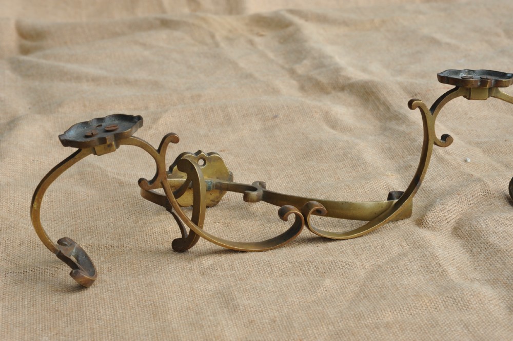 A set of three antique French cast bronze wall-mounted hat and coat hooks with scrolled upper arms and shaped lower pegs. View V
