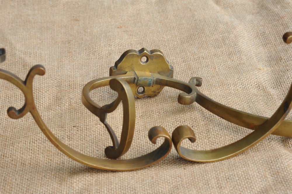 A set of three antique French cast bronze wall-mounted hat and coat hooks with scrolled upper arms and shaped lower pegs. View VI