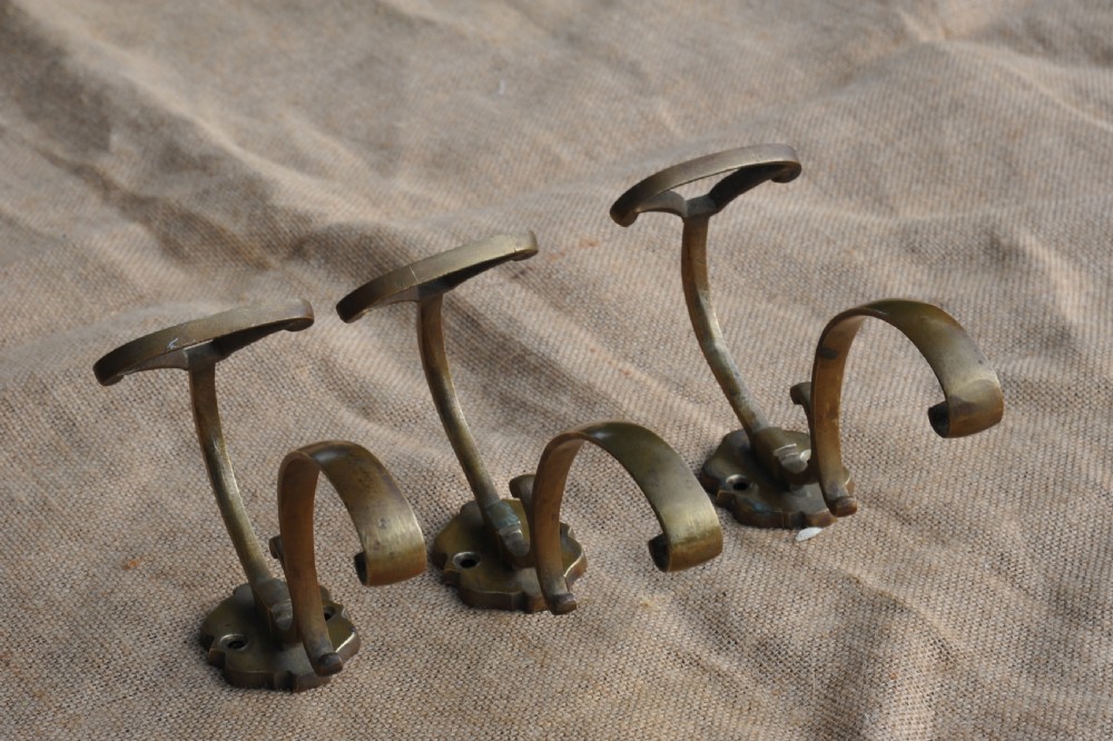 A set of three antique French cast bronze wall-mounted hat and coat hooks with scrolled upper arms and shaped lower pegs. View VIII