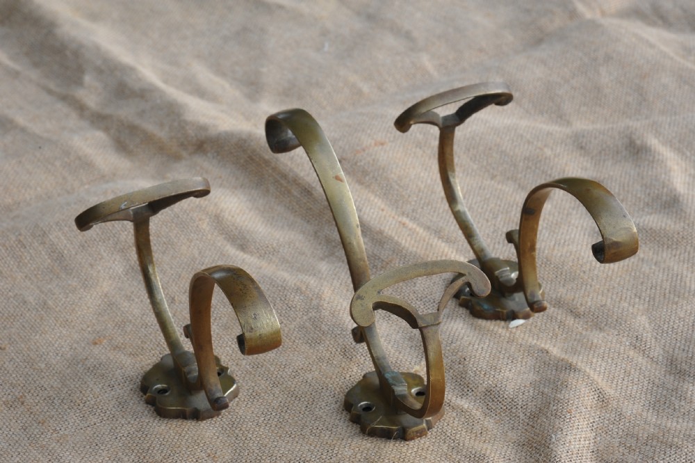 A set of three antique French cast bronze wall-mounted hat and coat hooks with scrolled upper arms and shaped lower pegs. View IX