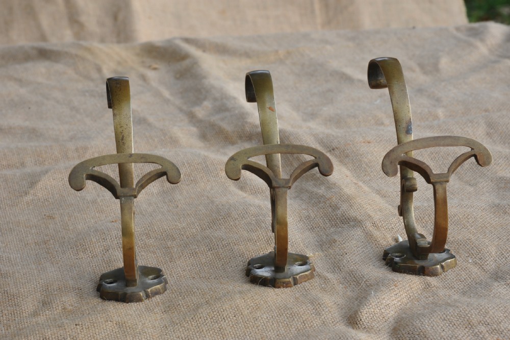 A set of three antique French cast bronze wall-mounted hat and coat hooks with scrolled upper arms and shaped lower pegs. View X