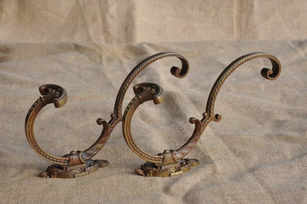A pair of ornate antique French cast bronze dual-prong wall hooks featuring scrolling upper arms and decorative detailed bases. View II