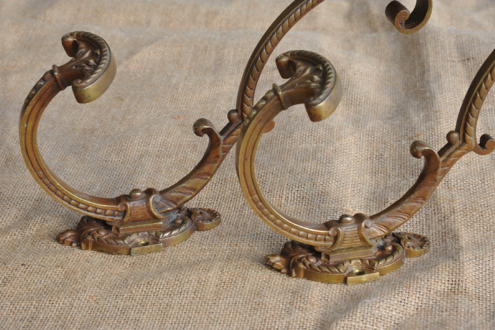 A pair of ornate antique French cast bronze dual-prong wall hooks featuring scrolling upper arms and decorative detailed bases. View IV