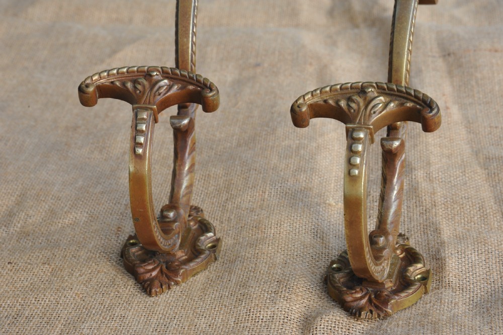 A pair of ornate antique French cast bronze dual-prong wall hooks featuring scrolling upper arms and decorative detailed bases. View VI