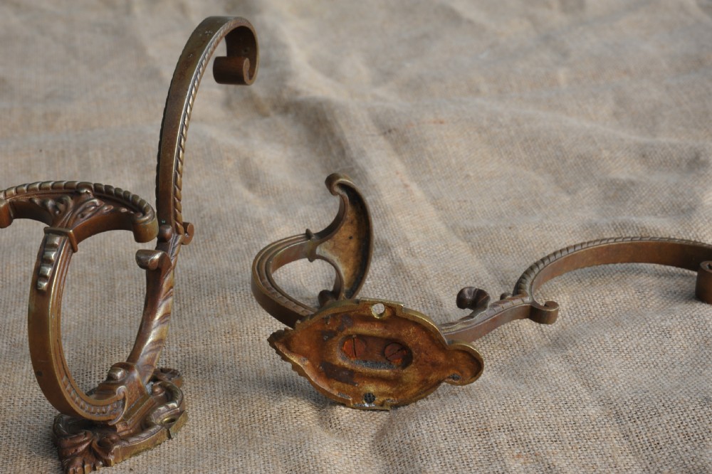 A pair of ornate antique French cast bronze dual-prong wall hooks featuring scrolling upper arms and decorative detailed bases. View VII