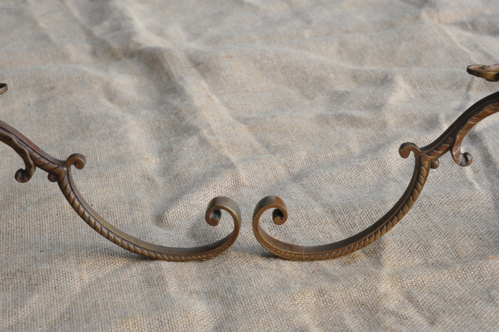 A pair of ornate antique French cast bronze dual-prong wall hooks featuring scrolling upper arms and decorative detailed bases. View X