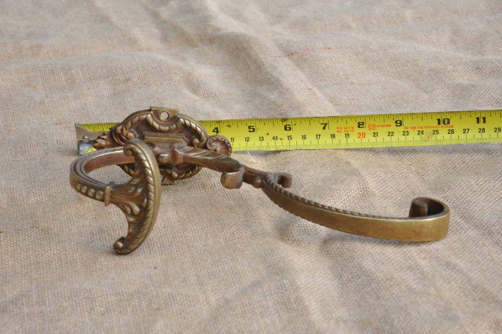 A pair of ornate antique French cast bronze dual-prong wall hooks featuring scrolling upper arms and decorative detailed bases. View XI