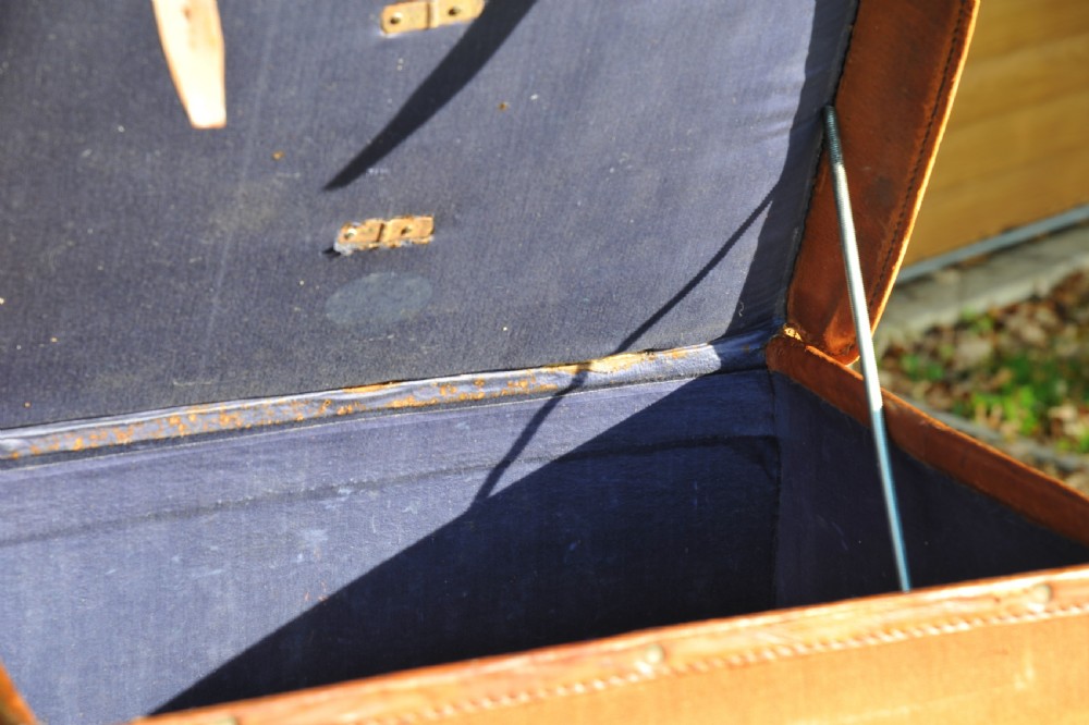 A square antique tan canvas travel case featuring stitched brown leather edging, a top carrying handle, brass rivets, and an authentic Paddington railway paper label. View X