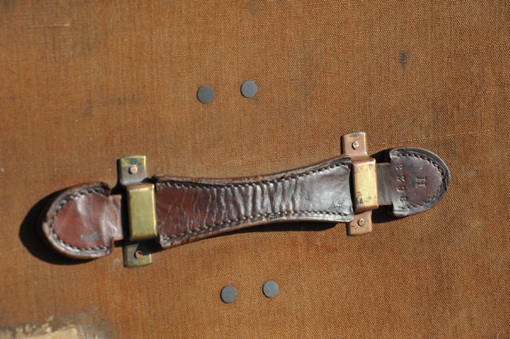 A square antique tan canvas travel case featuring stitched brown leather edging, a top carrying handle, brass rivets, and an authentic Paddington railway paper label. View XII