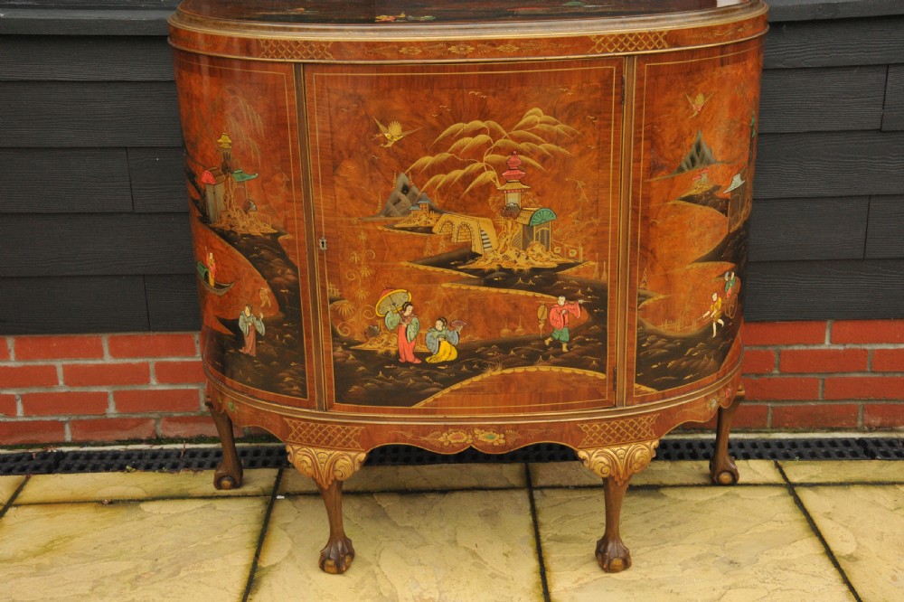 A circa 1910 semi-circular demi-lune cabinet featuring hand-painted Chinoiserie figures and landscapes with gilt details on cabriole legs. View VIII