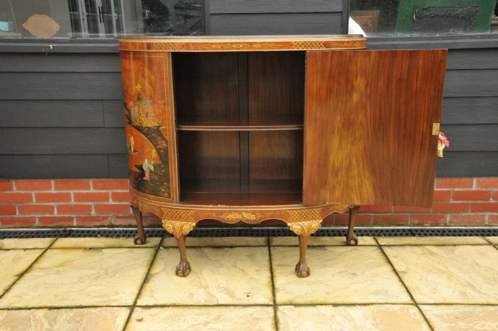 A circa 1910 semi-circular demi-lune cabinet featuring hand-painted Chinoiserie figures and landscapes with gilt details on cabriole legs. View XV