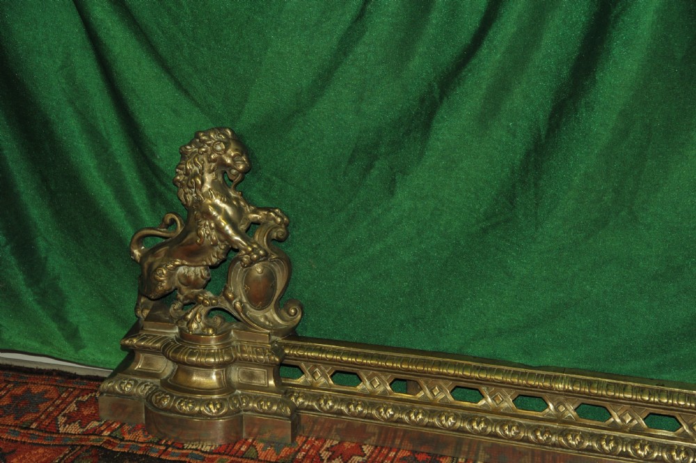 A cast brass Louis XV style fireplace fender featuring a central pierced lattice gallery flanked by two sculpted lions resting on shields. View II