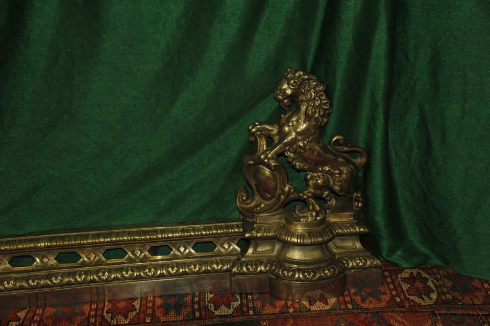 A cast brass Louis XV style fireplace fender featuring a central pierced lattice gallery flanked by two sculpted lions resting on shields. View III