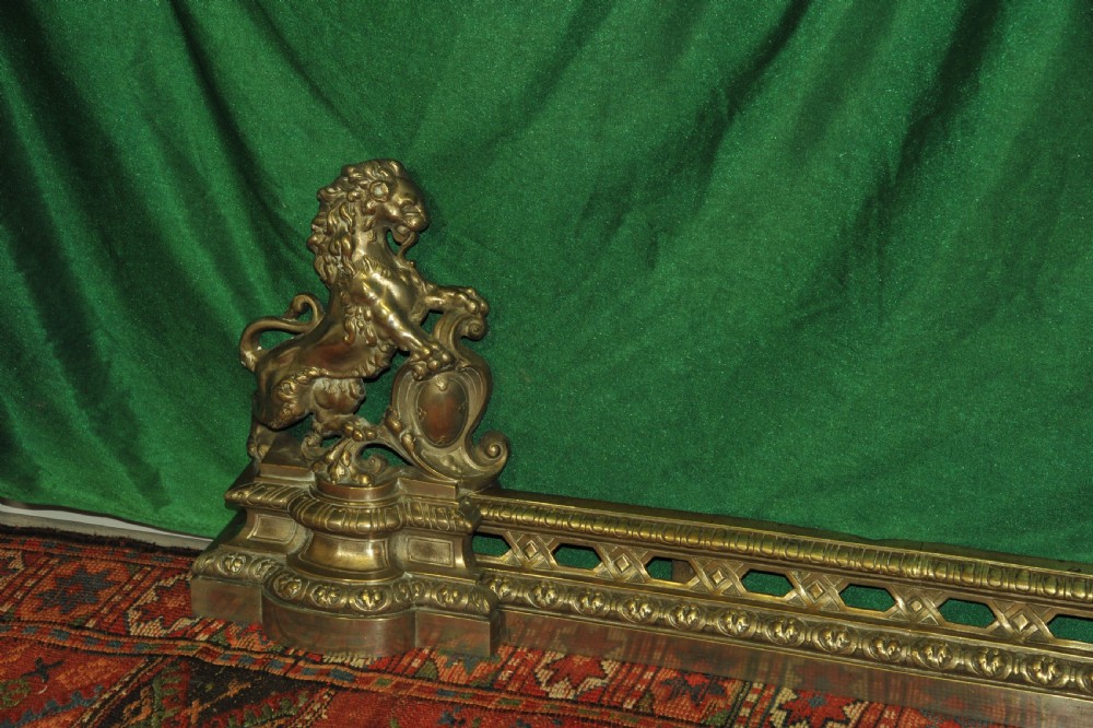 A cast brass Louis XV style fireplace fender featuring a central pierced lattice gallery flanked by two sculpted lions resting on shields. View IV