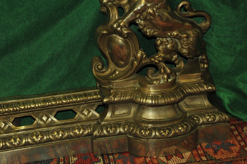 A cast brass Louis XV style fireplace fender featuring a central pierced lattice gallery flanked by two sculpted lions resting on shields. View IX