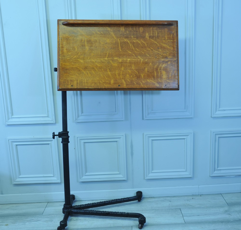 An adjustable oak reading table featuring a tilting rectangular top with a book ledge, supported on a black cast iron column and wheeled base. View V