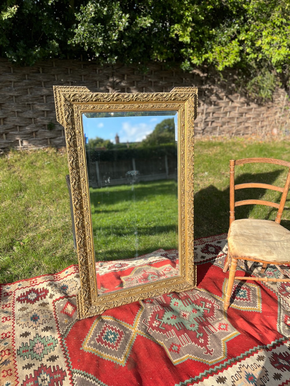 A large rectangular 19th-century French wall mirror featuring an ornate gold gilt gesso frame with floral relief details and bevelled glass.