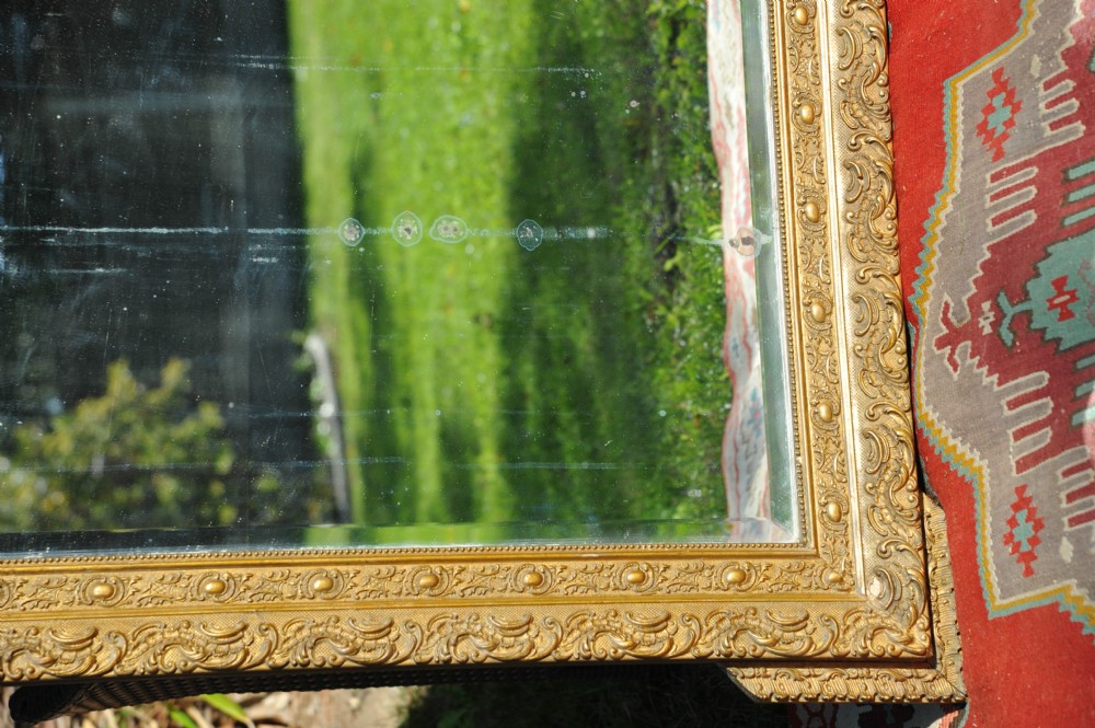 A large rectangular 19th-century French wall mirror featuring an ornate gold gilt gesso frame with floral relief details and bevelled glass. View IV