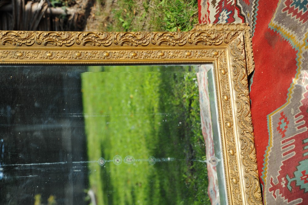 A large rectangular 19th-century French wall mirror featuring an ornate gold gilt gesso frame with floral relief details and bevelled glass. View V
