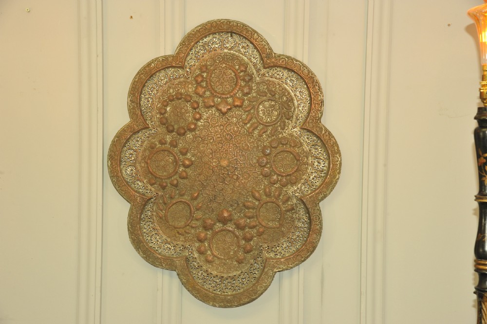An antique Kashmiri lobed copper tray featuring detailed repousse floral work, pierced openwork sections, and residual silver plating.
