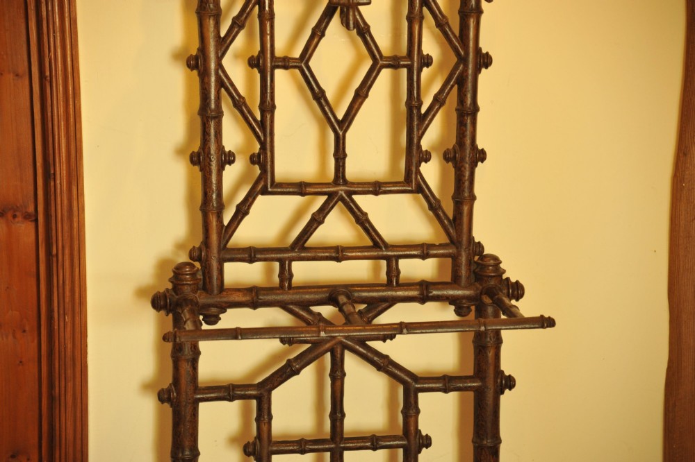 A late 19th-century French cast iron hall stand featuring a faux bamboo frame, central mirror, multiple hanging hooks, and an integrated umbrella rack with base drip trays. View II