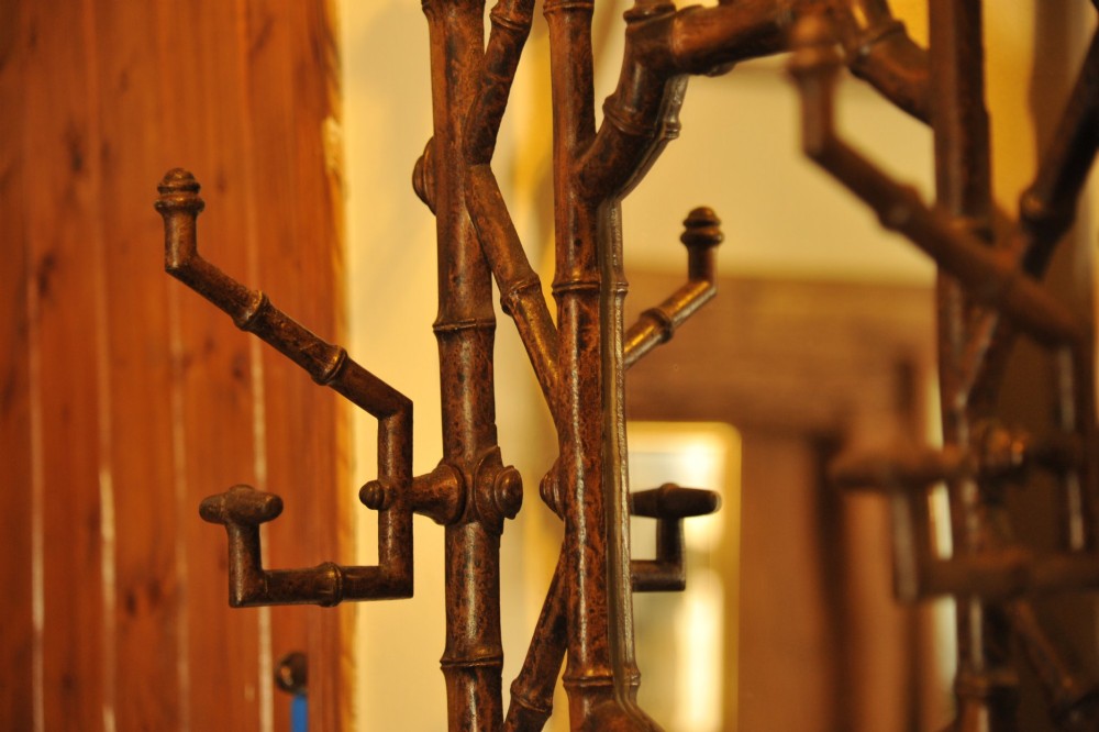 A late 19th-century French cast iron hall stand featuring a faux bamboo frame, central mirror, multiple hanging hooks, and an integrated umbrella rack with base drip trays. View IV