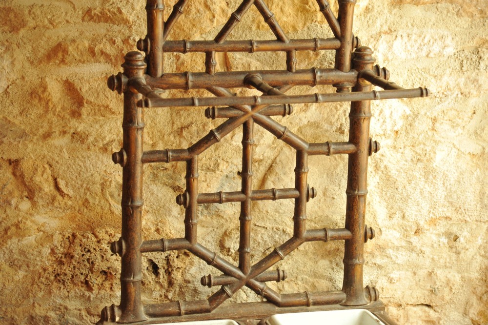 A late 19th-century French cast iron hall stand featuring a faux bamboo frame, central mirror, multiple hanging hooks, and an integrated umbrella rack with base drip trays. View V