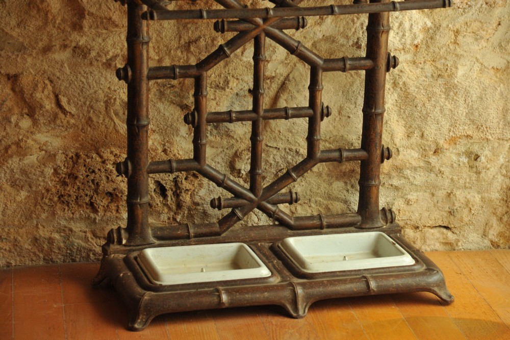 A late 19th-century French cast iron hall stand featuring a faux bamboo frame, central mirror, multiple hanging hooks, and an integrated umbrella rack with base drip trays. View VI