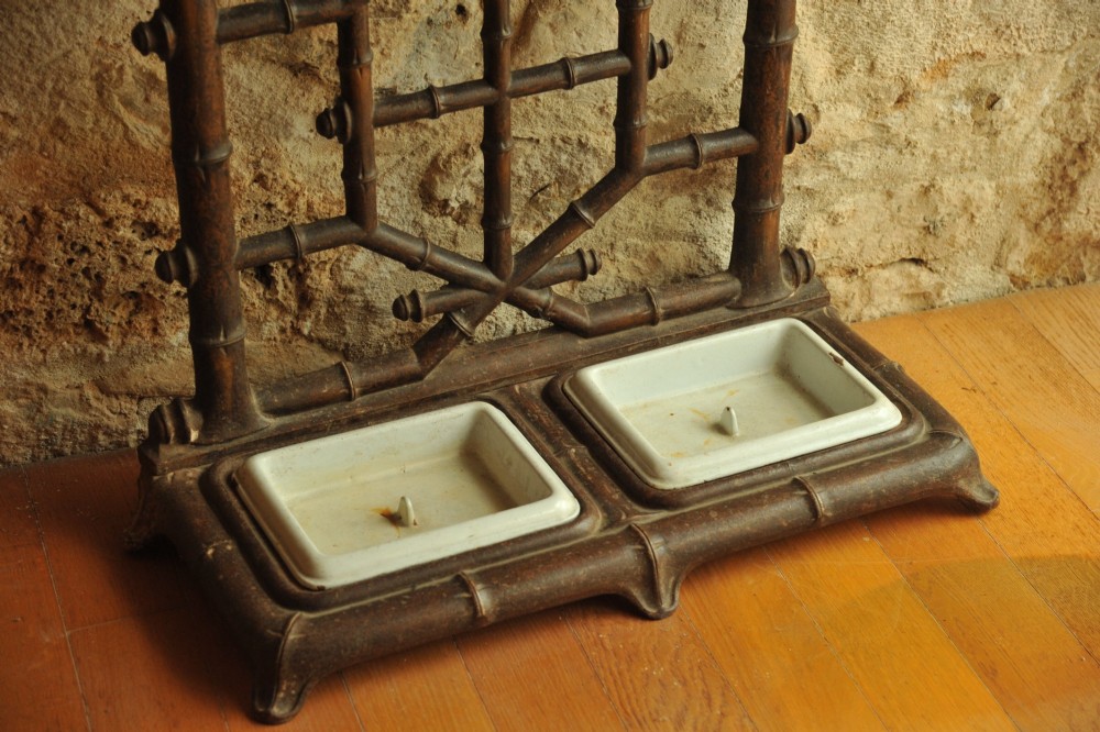 A late 19th-century French cast iron hall stand featuring a faux bamboo frame, central mirror, multiple hanging hooks, and an integrated umbrella rack with base drip trays. View X