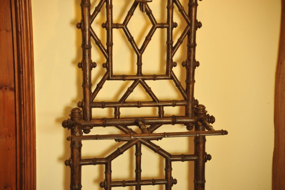 A late nineteenth-century French cast iron hall stand featuring a faux bamboo frame, central mirror, coat hooks, umbrella rail, and dual drip trays. View II