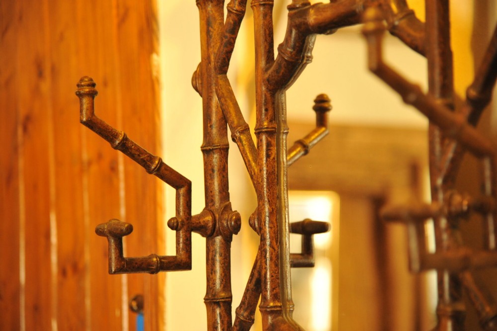 A late nineteenth-century French cast iron hall stand featuring a faux bamboo frame, central mirror, coat hooks, umbrella rail, and dual drip trays. View IV