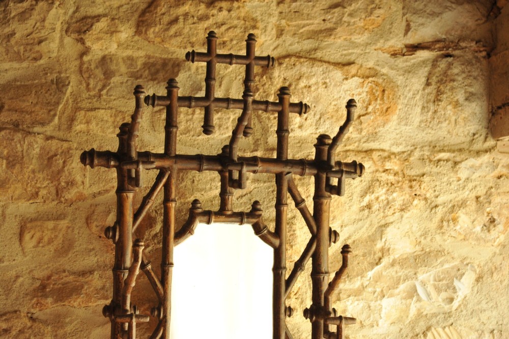 A late nineteenth-century French cast iron hall stand featuring a faux bamboo frame, central mirror, coat hooks, umbrella rail, and dual drip trays. View VIII