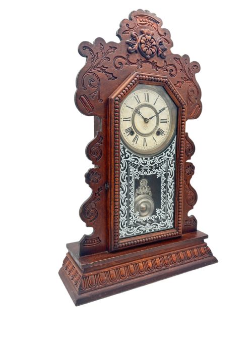 fig 2. A late 19th-century Ansonia gingerbread mantel clock crafted from dark carved oak with a stencilled glass pendulum door and Roman numeral dial.