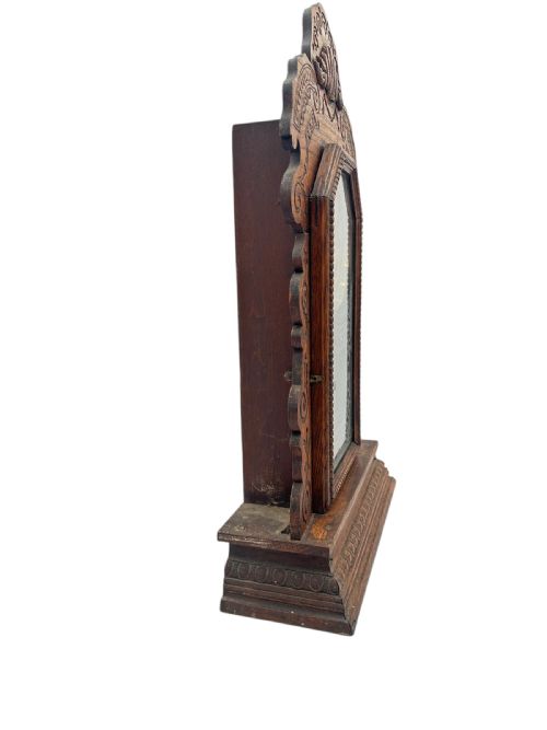 fig 2. An antique Victorian Ansonia gingerbread mantel clock crafted from carved oak with a round dial, brass pendulum, and stencilled glass door.