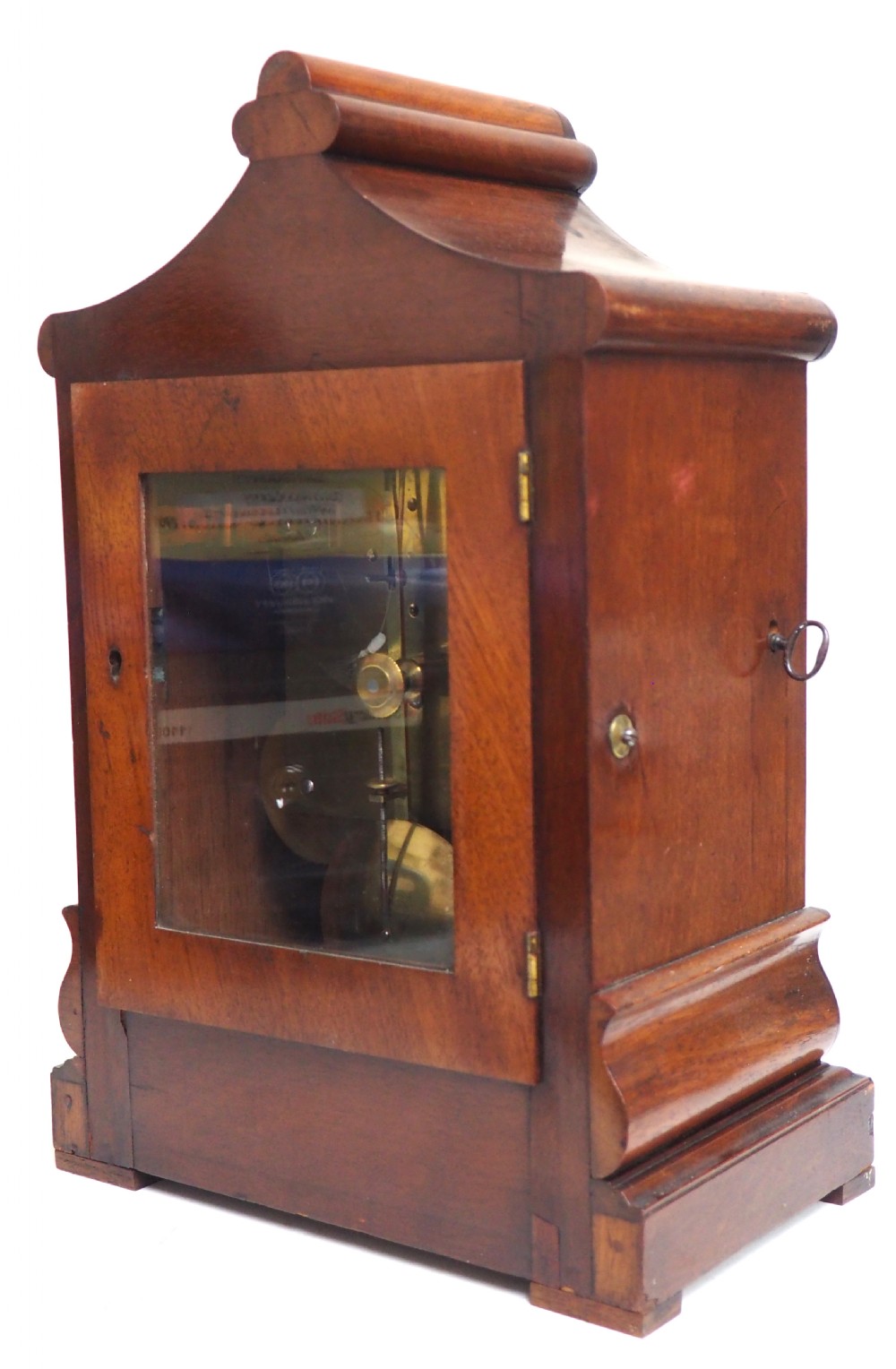 An antique Victorian flame mahogany bracket clock featuring carved leaf decoration, a round cream dial with Roman numerals, and a hinged brass bezel. View VIII