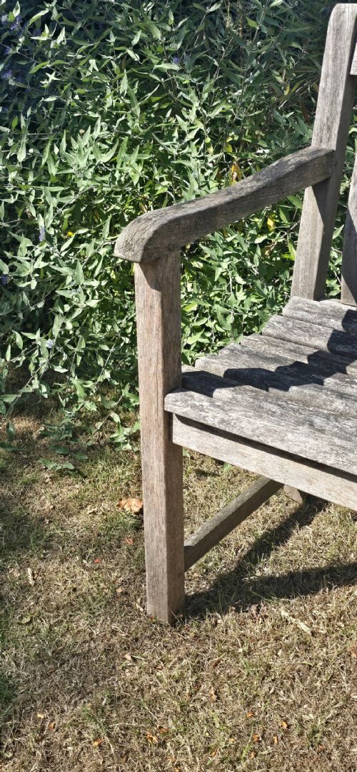 A weathered teak garden bench featuring a vertical slatted backrest, slatted seat, and straight legs connected by stretchers. View VI