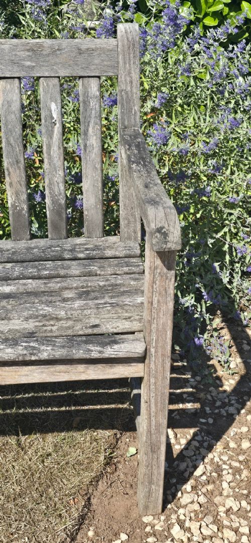 A weathered teak garden bench featuring a vertical slatted backrest, slatted seat, and straight legs connected by stretchers. View VII