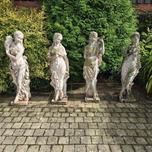 fig 1. A set of four weathered grey stone full-length classical female statues representing the Four Seasons on rectangular bases.