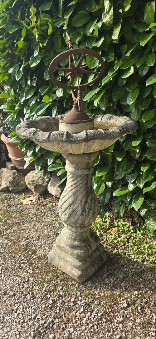 A weathered stone bird bath featuring a spiral-carved pedestal support topped with a rust-brown cast iron armillary sphere. View VI