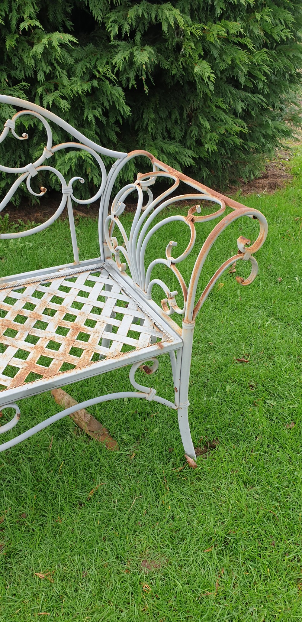 A pair of grey painted wrought iron garden benches featuring ornate scrollwork backrests and woven lattice seats. View III