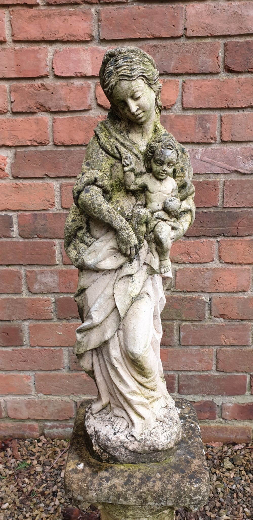 A pair of weathered grey stone statues depicting the Madonna and Child, each mounted on a square tapered plinth base. View III