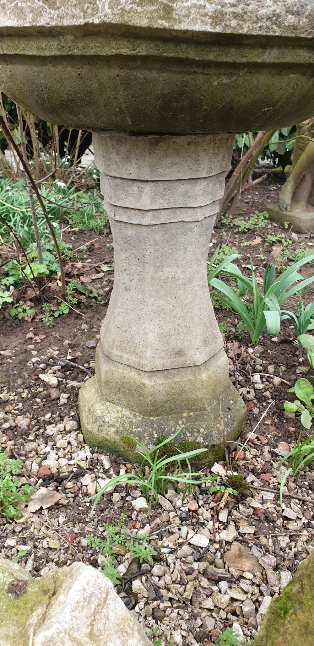 A weathered grey cast stone bird bath featuring an octagonal basin resting upon a tapered faceted pedestal base. View II