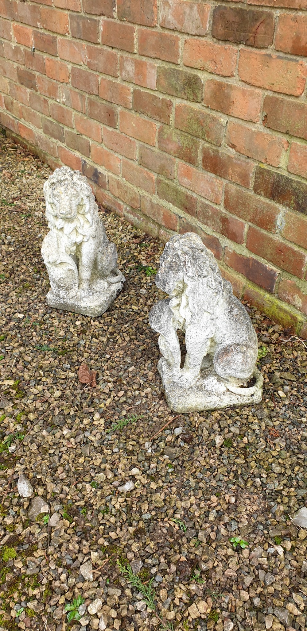 A pair of weathered grey stone finials sculpted as seated lions holding shields on integral rectangular bases. View IV