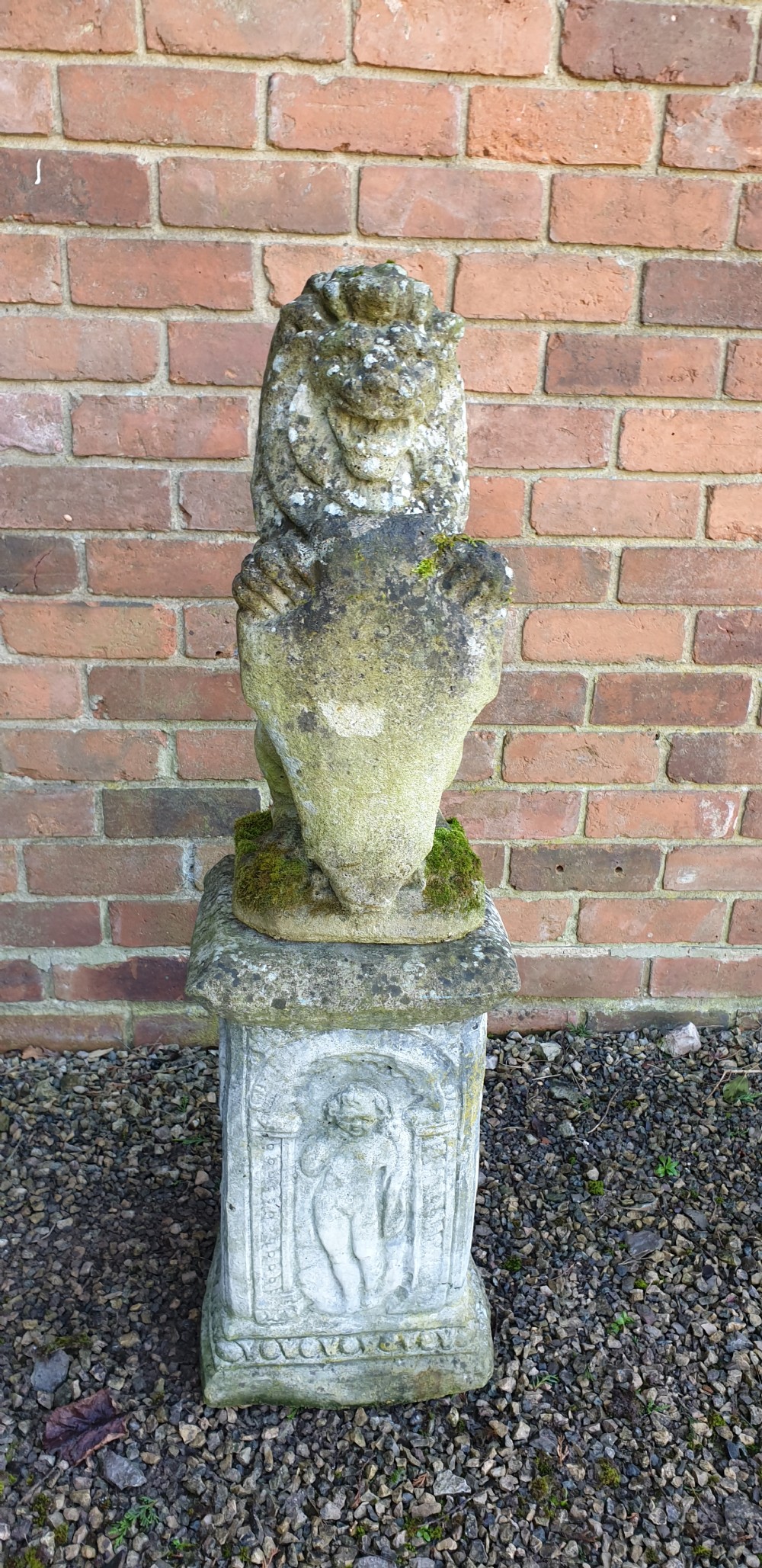 A pair of weathered grey stone seated lion statues holding shields, mounted on relief-carved rectangular plinths. View III