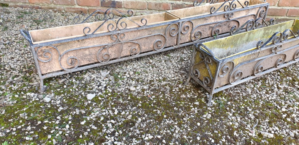 A pair of long rectangular wrought iron garden troughs featuring open scrollwork frames and inner metal insert boxes. View V