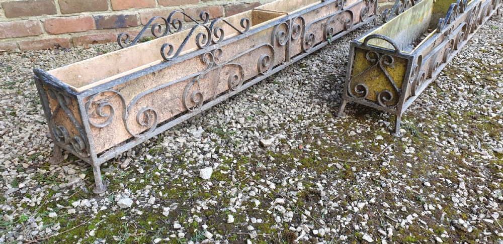 A pair of long rectangular wrought iron garden troughs featuring open scrollwork frames and inner metal insert boxes. View VI