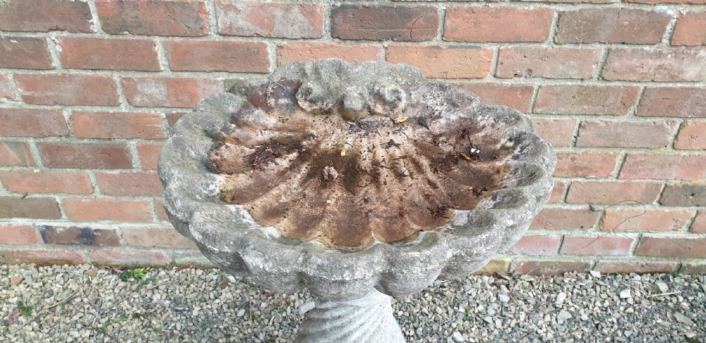 A weathered grey stone bird bath featuring a scalloped shell-shaped top basin set upon a spiral twisted pedestal column and square base. View IV