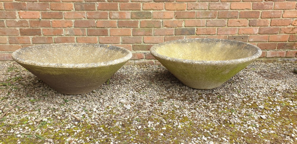 A pair of large shallow conical weathered stone pancheon bowls with visible moss patina resting on gravel. View III