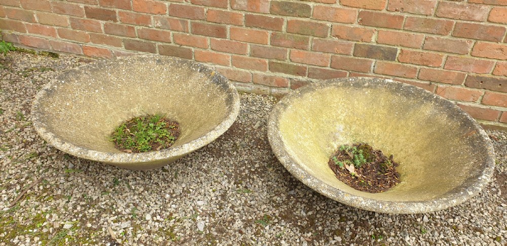 A pair of large shallow conical weathered stone pancheon bowls with visible moss patina resting on gravel. View IV